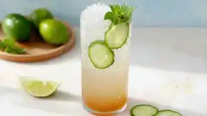 Refreshing coconut water mocktail with cucumber slices, mint, and lime served over ice in a tall glass.