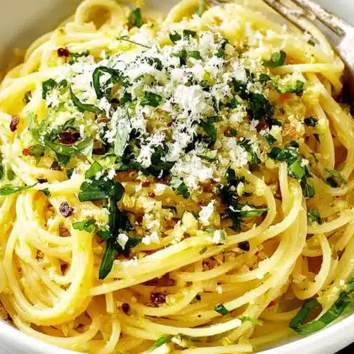 Creamy lemon garlic spaghetti topped with fresh parsley, Parmesan, and a sprinkle of red pepper flakes.