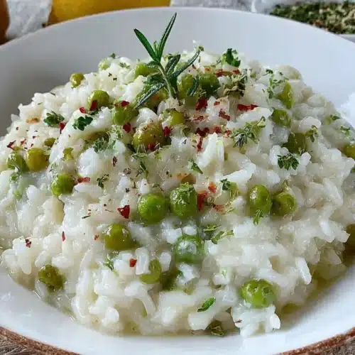 Close-up bowl of creamy lemongrass risotto recipe with green peas, rosemary, and chili flakes on rustic linen.