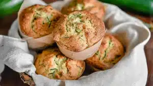 Basket of warm sourdough zucchini muffins wrapped in a linen towel