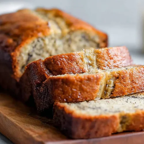 Close-up of sliced buttermilk banana bread on a wooden board with a soft, tender crumb.