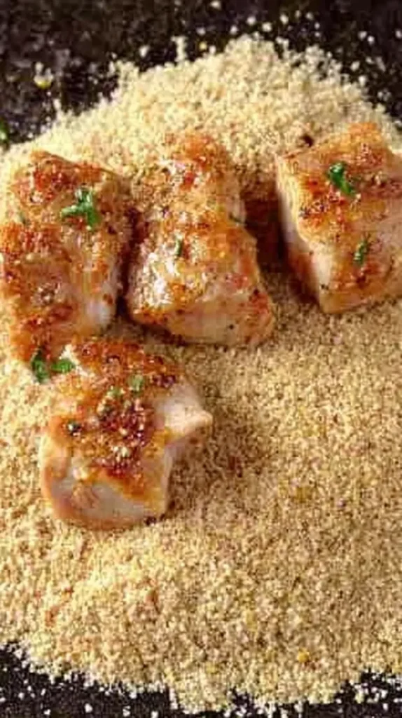 Bites of seared chicken resting on a bed of seasoned breadcrumbs for Chicken Spiedini.
