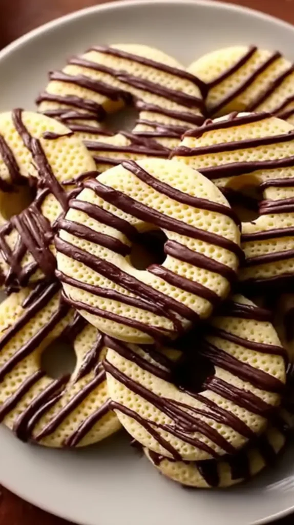 Fudge Stripe Cookies on a plate, buttery ring-shaped shortbread with dark chocolate stripes