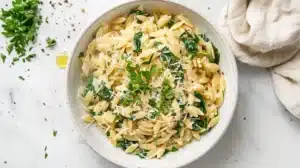 Close-up of creamy garlic parmesan orzo with spinach and black pepper on a fork.