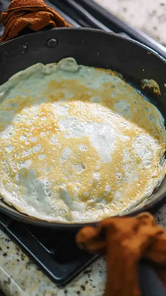 Norwegian Pancakes batter set in hot pan with lacy golden edges