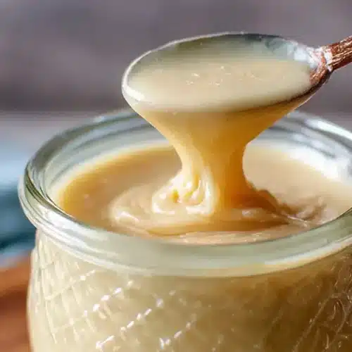 whipped honey recipe dripping smoothly from a spoon into a jar
