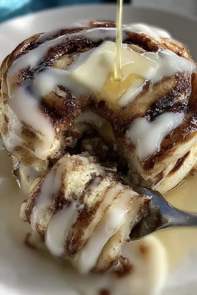 Cinnamon Roll Pancakes: Easy, Fluffy & Wonderful 3 Close-up of Cinnamon Roll Pancakes cut open with a fork, showing soft fluffy layers and melted cinnamon filling