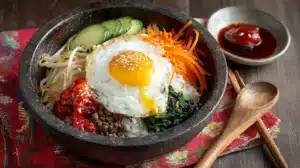 Easy Bibimbap with Ground Beef topped with a sunny-side-up egg, assorted vegetables, rice, and gochujang sauce served on the side