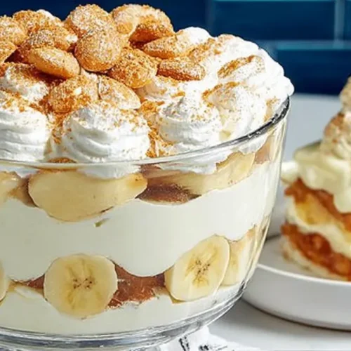 Magnolia Bakery banana pudding served in a large glass trifle with banana slices, vanilla wafers, and whipped cream