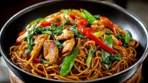 Easy Chicken Lo Mein recipe noodles piled high in a black bowl with chicken pieces, peppers, and snow peas.