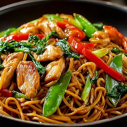 Easy Chicken Lo Mein recipe noodles piled high in a black bowl with chicken pieces, peppers, and snow peas.