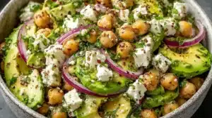 Wide bowl of chickpea feta avocado salad with red onion and herbs
