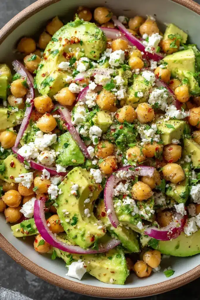 Overhead view of chickpea avocado salad with feta cheese and red onion in a gray bowl