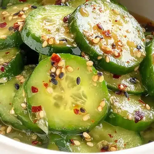 Japanese cucumber salad with sesame seeds, chili flakes, and soy-based dressing in a white bowl