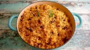Puerto Rican Rice Recipe: Easy Arroz con Gandules Blue Dutch oven filled with Puerto Rican rice and beans, set on a weathered wooden table with a soft turquoise finish.