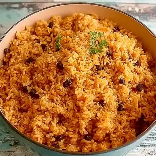 Blue Dutch oven filled with Puerto Rican rice and beans, set on a weathered wooden table with a soft turquoise finish.