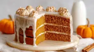 Pumpkin Cake with Cinnamon: Simple, Stunning, Flavor-Packed Pumpkin Cake with Cinnamon frosted with cinnamon cream cheese icing, sliced to show layered pumpkin cake on a marble board