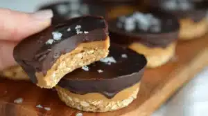 No Bake Peanut Butter Oat Cups bitten in half showing layers of oats, creamy peanut butter, and smooth chocolate topping