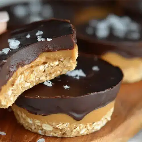 No Bake Peanut Butter Oat Cups bitten in half showing layers of oats, creamy peanut butter, and smooth chocolate topping