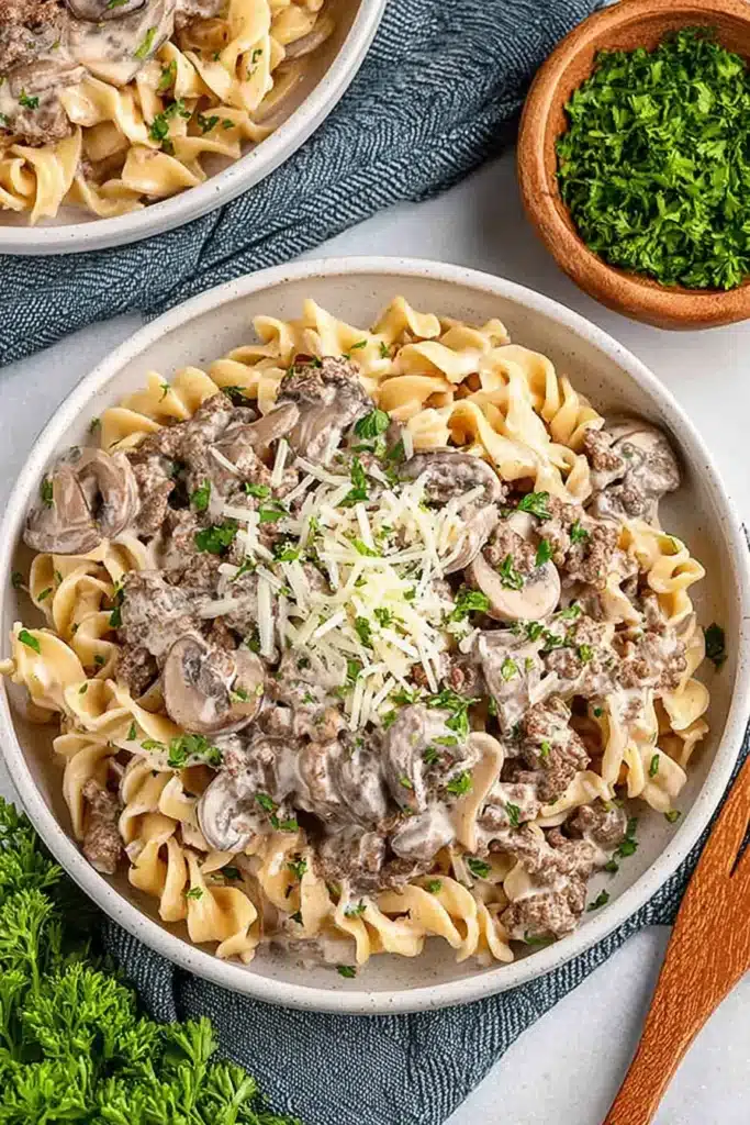 Ground Beef Stroganoff served over buttery egg noodles with tender mushrooms, creamy sauce, Parmesan, and fresh parsley