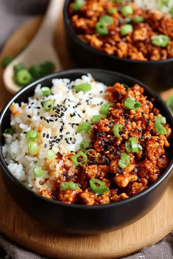 Low Carb Firecracker Ground Chicken served in a bowl with fluffy rice, sesame seeds, and green onions
