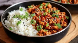 Low Carb Firecracker Ground Chicken: Quick, Irresistible Skillet Low Carb Firecracker Ground Chicken topped with sesame seeds and green onions in a black bowl