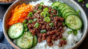 Korean Ground Beef Bowl served over white rice with saucy ground beef, sliced cucumbers, shredded carrots, sesame seeds, and chopped green onions