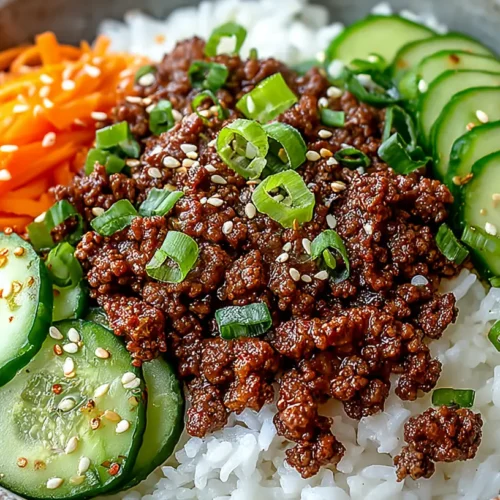 Korean Ground Beef Bowl served over white rice with saucy ground beef, sliced cucumbers, shredded carrots, sesame seeds, and chopped green onions