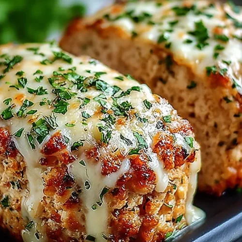 Garlic Parmesan Chicken Meatloaves topped with melted cheese and fresh parsley on a dark serving plate