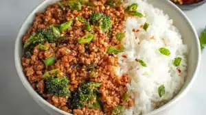 Firecracker Ground Chicken Bowl served with spicy ground chicken, broccoli, sesame seeds, green onions, and steamed white rice