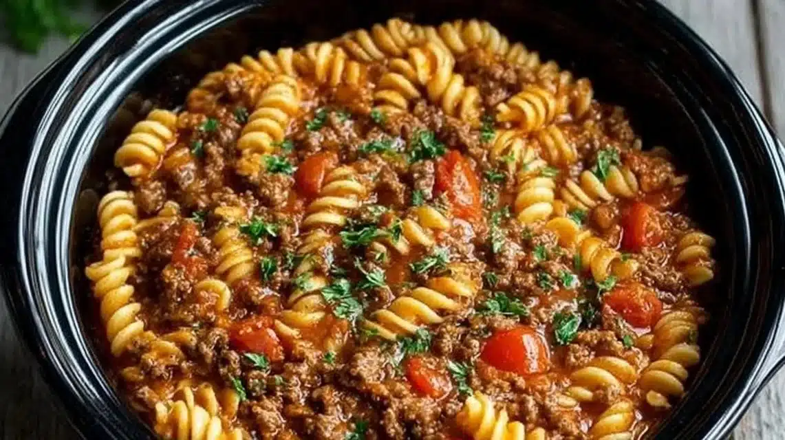Slow Cooker Taco Pasta (Creamy, Beefy, and So Simple) 1 Crockpot Taco Pasta served in a bowl with cheese and herbs