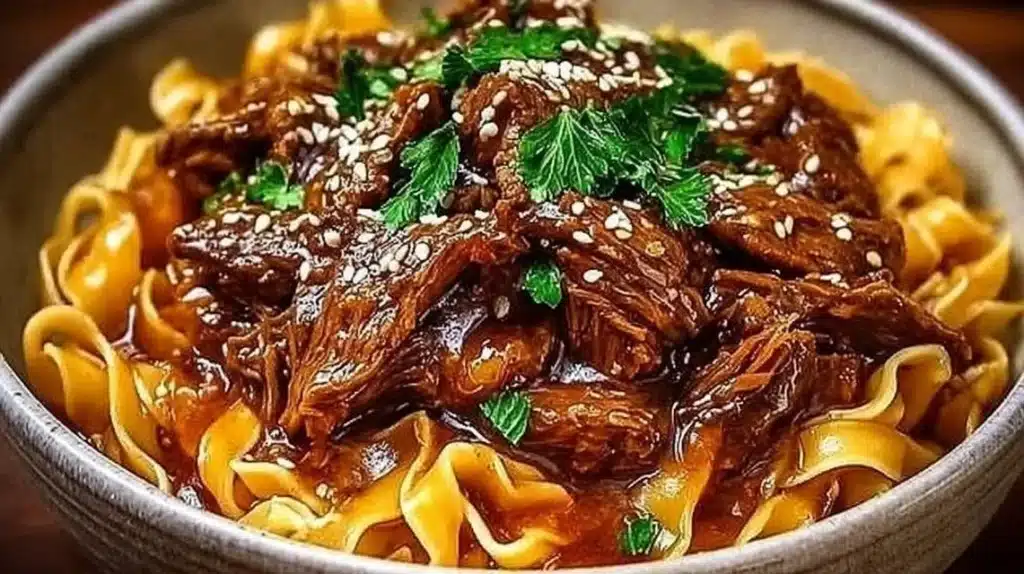Bowl of Korean beef noodles topped with fresh herbs and chili flakes