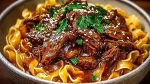 Bowl of Korean beef noodles topped with fresh herbs and chili flakes
