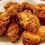 Golden crispy fried chicken served on a plate with dipping sauce