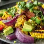 Charred corn avocado salad with roasted red onions served in a bowl