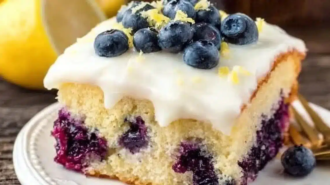A slice of moist Lemon Blueberry Cake topped with fresh blueberries and lemon zest.