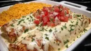 Plate of delicious queso chicken enchiladas topped with cheese and fresh herbs.