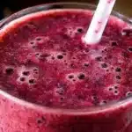 Cherry spinach smoothie in a glass, garnished with fresh cherries and spinach leaves.