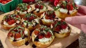Creamy Ricotta Crostini with Roasted Tomatoes and Basil Creamy ricotta crostini topped with roasted tomatoes and basil on a wooden board