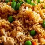 Delicious plate of ground chicken fried rice garnished with green onions and vegetables