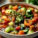 Bowl of hearty plant-based veggie stew with fresh vegetables and herbs.